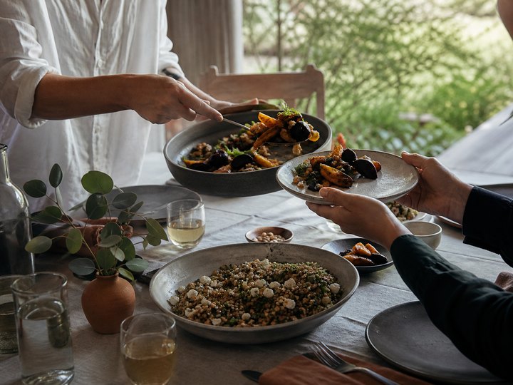 Friends sharing seasonal vegetable dishes on a verandah